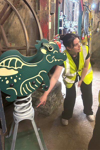 Playsafe staff showing children a green spring dragon playground apparatus